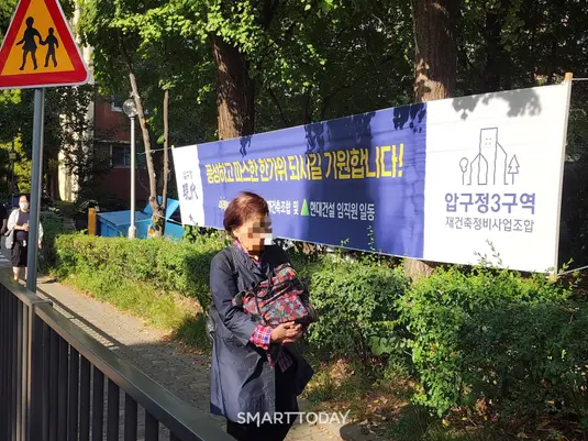 한 시민이 압구정3구역 내 현대건설 현수막 앞 인도를 걷고 있다. 출처=김종현 기자