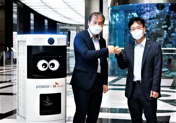 ◇SK텔레콤과 포스코가 자율주행 방역로봇 ‘Keemi’이 지켜보는 가운데 산업안전 등 AI기반 기술협력을 위한 업무 협약을 체결하고 기념촬영을 하고 있다.(사진:SKT)