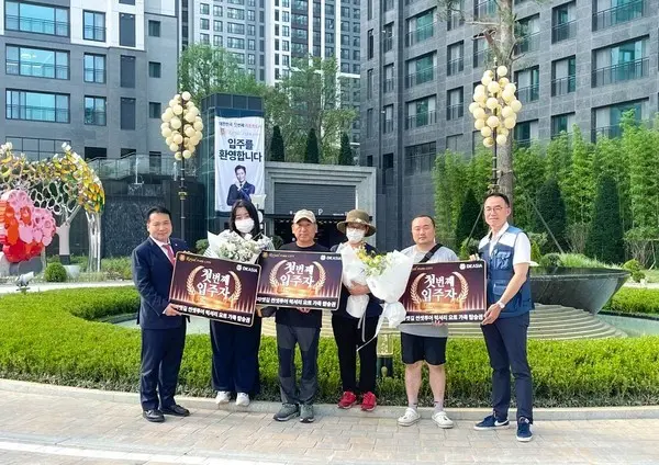 DK아시아 김효종 대표이사(왼쪽 첫번째)가 2단지 첫번째 입주자에게 꽃다발과 선물을 전달했다(사진제공. DK아시아)