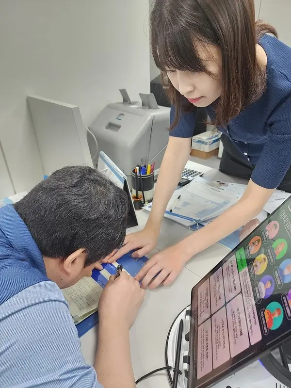 시각장애인이 자필카드에 맞춰 서명하고 있다. [출처: 신한은행]