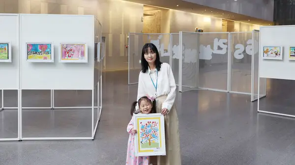 GS건설 임직원이 자녀와 본사 사옥 1층에 전시중인 ‘GS건설에 왔나 봄’ 그림 전시전을 관렴하고 있다. (사진제공. GS건설)