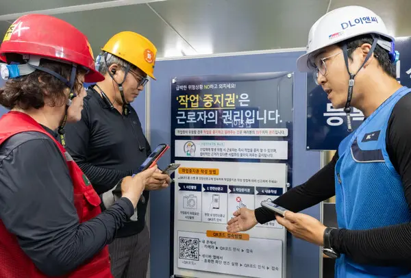 DL이앤씨 현장 안전관리자(우측 첫번째)가 현장 근로자들에게 안전신문고 접속 및 작업중지권 사용법에 대해 설명하고 있다. (사진제공. DL이앤씨)