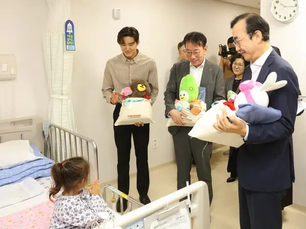 김우민 KB금융그룹 후원 수영선수(왼쪽), 이재근 KB국민은행장(가운데), 이세훈 금융감독원 수석부원장(오른쪽)이 22일 부천세종병원에서 심장병 수술을 받은 캄보디아 어린이에게 인형과 전통과자를 선물했다. [출처: KB국민은행]