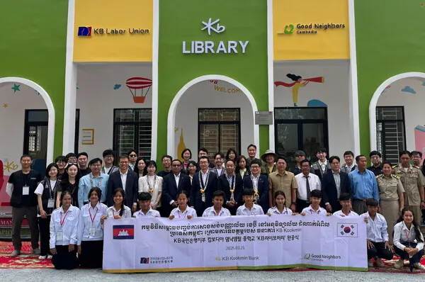 지난 21일 캄보디아 프놈펜에 위치한 댐낙앰필 중학교에서 ‘KB라이브러리’ 개관식이 열렸다. 정훈영 KB국민은행지부 수석부위원장(두 번째 줄 왼쪽 7번째), 옴쌈이온 KB 프라삭 은행장(두 번째 줄 왼쪽 6번째), 장동원 굿네이버스 캄보디아 대표(두 번째 줄 왼쪽 9번째)가 이날 개관식에서 기념촬영을 하고 있다. [출처: KB국민은행]