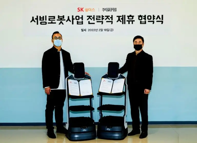 ◇우아한형제들 김민수 서빙로봇실장(왼쪽)과 SK쉴더스 김윤호 전략사업그룹장이 18일 서울 문정동 가든파이브에서 