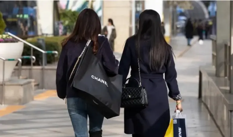 서울 한 거리에서 샤넬백과 쇼핑백을 맨 사람들이 지나가고 있다. 출처=CNBC 갈무리