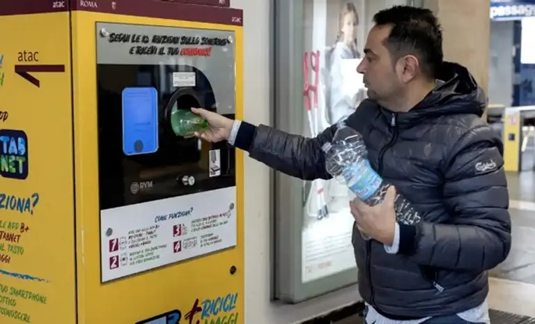한 사람이 이탈리아 지하철 역사 내부에 있는 기기에 병을 반환하려 하고 있다. 출처=가디언/게티이미지
