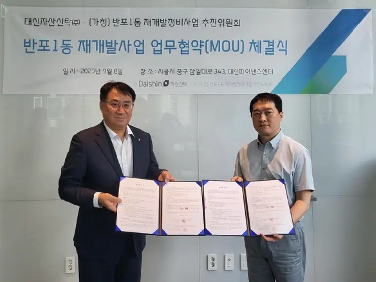 대신자산신탁 김송규 대표(왼쪽)와 반포1동 주택재개발 추진위원장이 반포1동 재개발사업 업무협약 체결 기념 촬영을 하고 있다.