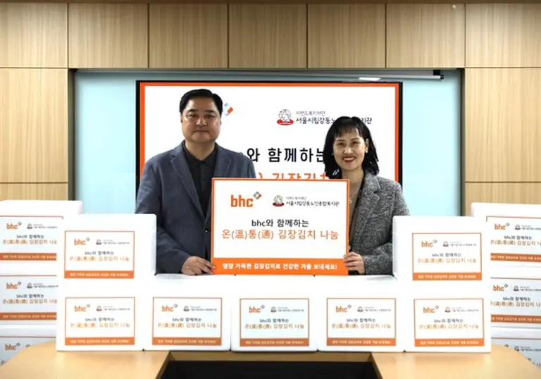 bhc그룹 임인엽 이사(좌측)가 김장김치를 전달한 후 서울시립 강동노인종합복지관 성미선 관장(우측)과 함께 기념촬영을 하고 있다.