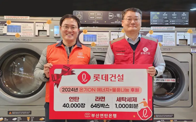 윤수준 롯데건설 영남지사장(오른쪽)과 강정칠 부산연탄은행 대표가 연탄·라면·세탁세제 기증판 전달식을 진행하고 있다. (사진제공. 롯데건설)