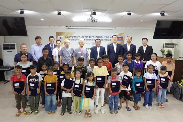 KB국민은행과 헤브론의료원이 지난 12일 캄보디아 수도 프놈펜 소재 헤브론의료원에서 심장병 수술아동 장학금 수여식을 열었다. 뒷줄 왼쪽 4번째부터 배기안 헤브론병원장, 김우정 헤브론의료원장, 옴 쌈은 KB프라삭은행장, 김현종 KB프라삭은행 부행장 등이 수여식에 참석했다. [출처: KB국민은행]