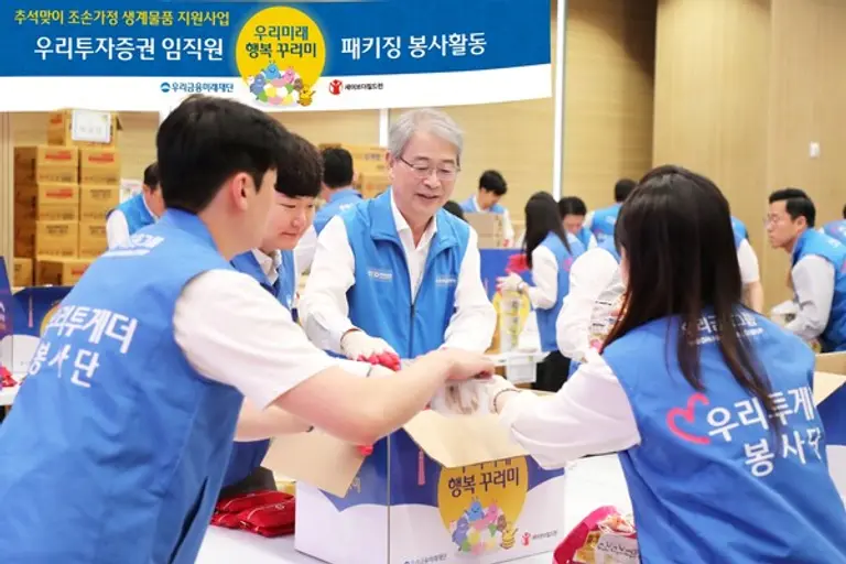 임종룡 우리금융그룹 회장(가운데)과 남기천 우리투자증권 대표가 지난 9일 임직원과 함께 16가지 생필품을 담아 ‘우리미래 행복 꾸러미’를 준비했다. [출처: 우리금융그룹]