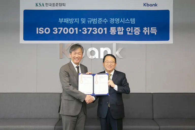 케이뱅크 최우형 은행장(왼쪽)과 한국표준협회 강명수 회장이 지난 17일 서울 중구 을지로 케이뱅크 본사 대회의실에서 열린 ISO37001·37301 통합 인증 수여식 직후 악수를 나눴다. [출처: 케이뱅크]