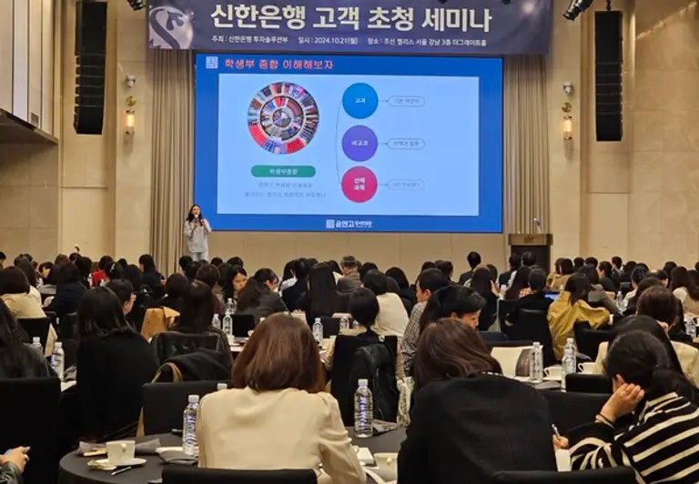 윤앤고 입시컨설팅의 윤여정 컨설턴트가 지난 21일 열린 ‘2024 우수고객 초청 세미나’에서 내년 대학입시 전략을 설명하자, 학부모들이 열심히 필기하고 있다. [출처: 신한은행]