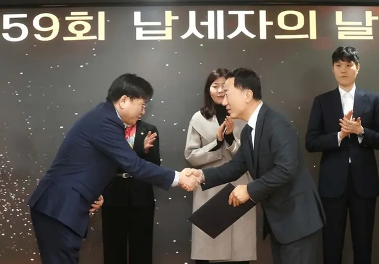 (오른쪽)유신열 신세계디에프 대표가 (왼쪽)김종호 인천공항본부세관장에게 모범납세자 경제부총리 표창을 받고 악수를 나누고 있다.