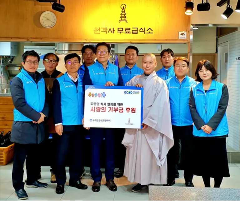우리금융에프앤아이 김건호 대표이사(왼쪽 다섯 번째), 전성찬 상무(왼쪽 세 번째), 원각사 원경스님(왼쪽 일곱 번째)이 지난 18일 서울 종로구 탑골공원 인근 원각사 무료급식소에서 열린 후원금 전달식에서 기념촬영을 하고 있다. [출처: 우리금융그룹]