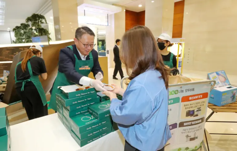 정진완 우리은행장(왼쪽)이 22일 제55회 지구의 날을 맞아 임직원 자원순환 캠페인 ‘Smart Fun(전자기기 자원순환 쉽게, 안전하게, 즐겁게!)’에서 폐기기를 기부한 임직원에 사은품을 전달했다. [출처: 우리은행]