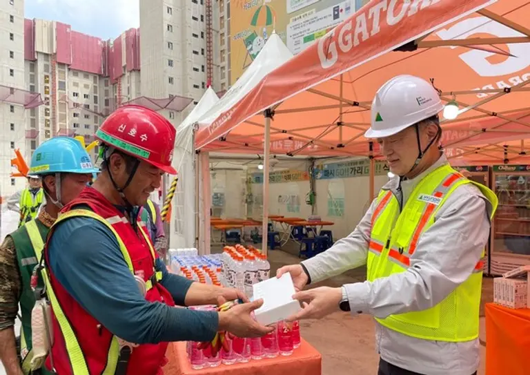 현대건설 CSO 황준하 전무가 근로자에게 수분 보충과 탈수 예방을 위한 이온음료와 쿨링스프레이를 직접 전달하고 있다. (사진제공=현대건설)