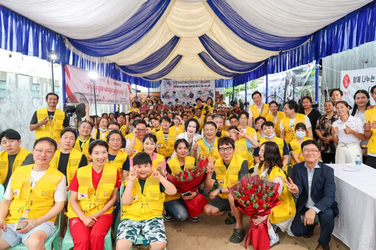 롯데장학재단 장혜선 이사장(세 번째 줄 가운데), 대한정형외과의사회 김완호 회장(두 번째 줄 여섯 번째), 피아비한캄사랑재단 스롱 피아비 대표이사(두 번째 줄 다섯 번째) 및 의료진들과 봉사 관계자, 캄보디아 현지 주민들이 함께 기념사진을 촬영하고 있다.