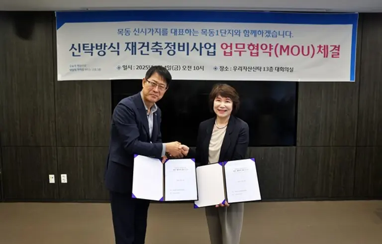 김범석 우리자산신탁 대표(왼쪽)와 정현숙 목동1단지 재건축준비위원장(오른쪽)이 재건축 협력을 다짐하며 악수를 하고있다.