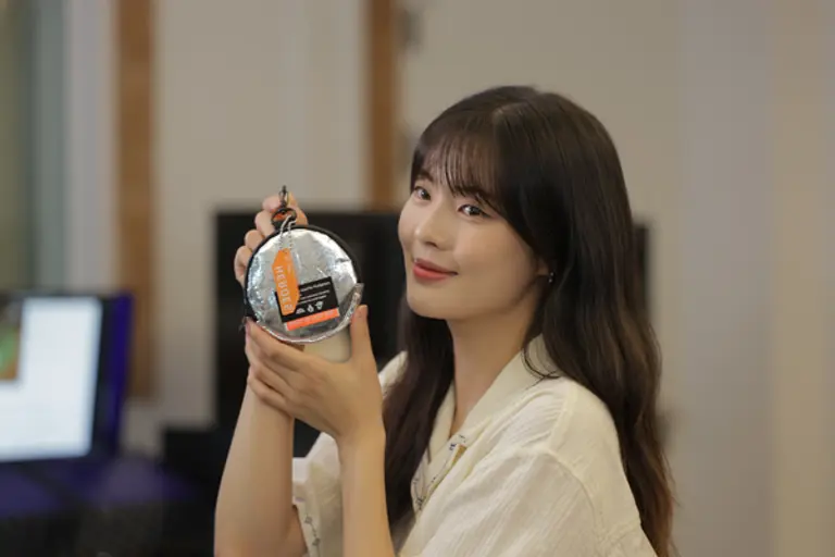 배우 이선빈이 ‘국민히어로즈’ 캠페인 리워드인 업사이클링 파우치와 넘버링 키링을 들고 사진촬영을 하고 있다(사진제공=희망브리지)