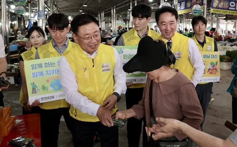 박상형 한전KDN 사장이 추석맞이 전통시장 장보기 행사의 일환으로 다회용 시장 바구니를 시민에게 나눠주고 있다.