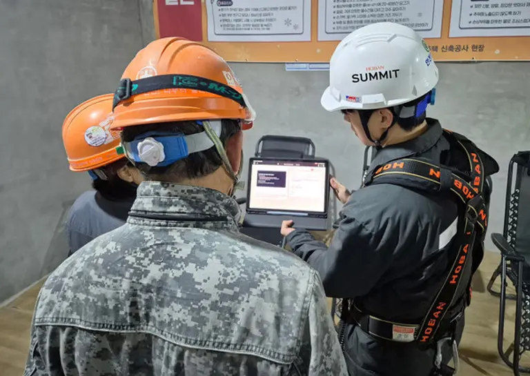 호반건설 직원이 건설 현장에서 AI 동시번역 플랫폼 ‘호반커넥트’를 활용해 근로자들과 대화하고 있다. (사진제공=호반건설)