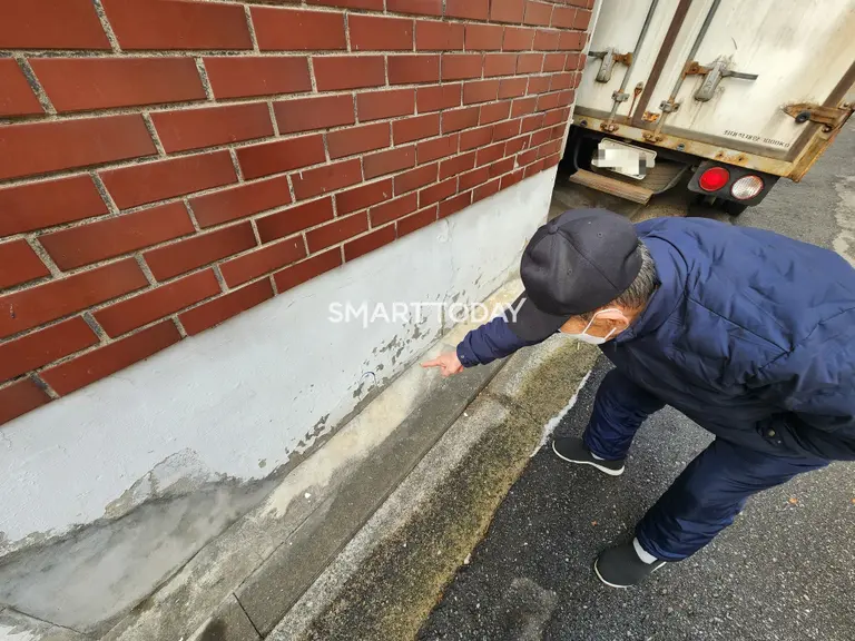 한 주민이 상봉13구역 노후 주거단지 외벽을 가리키고 있다. 출처=김종현 기자