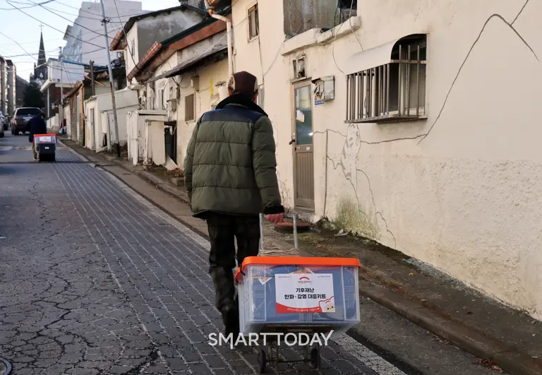  인천 동구 괭이부리마을 쪽방촌 거주민이 기후재난 한파·감염 대응키트를 수령해 이동하고 있다(사진제공=희망브리지)