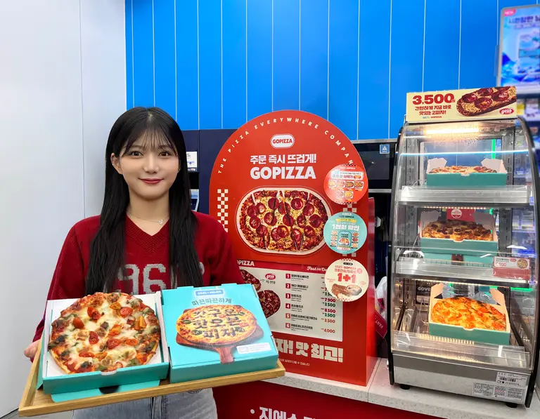 GS25에서 모델이 배달의민족과 협업해 출시한 피자를 들고 포즈를 취하고 있다. (사진=GS리테일)