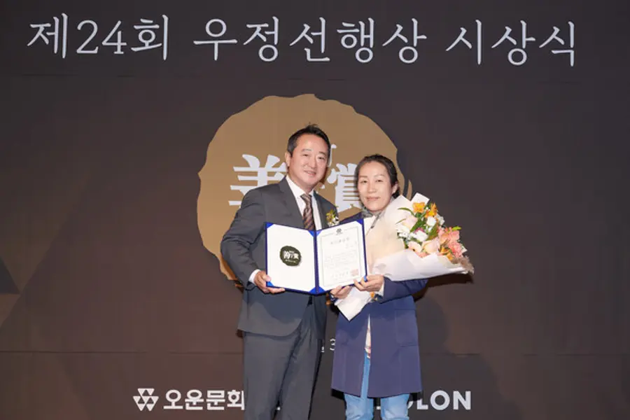 이웅열 오운문화재단 이사장(왼쪽)이 우정선행상 대상을 수상한 김선자(53) 씨와 기념사진을 촬영하고 있다.(사진제공=코오롱)