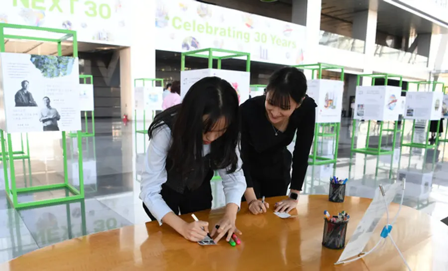 포스코이앤씨가 30주년을 맞아 30개의 성공스토리를 담은 전시회를 개최했다. 포스코 직원들이 즉석사진에 응원메시지를 적고 있다. (사진제공=포스코이앤씨)