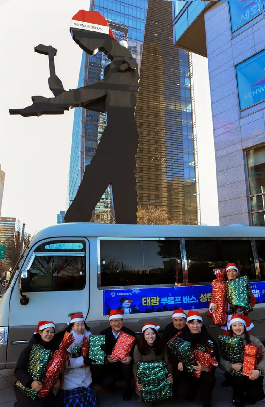 18일 오전 광화문 흥국생명빌딩 앞 해머링맨 문화광장에서 태광산업·흥국생명·흥국화재·티알엔 임직원들이 산타 복장을 하고 '태광 루돌프 버스' 출정식 기념촬영을 하고 있다.(사진제공=태광그룹)