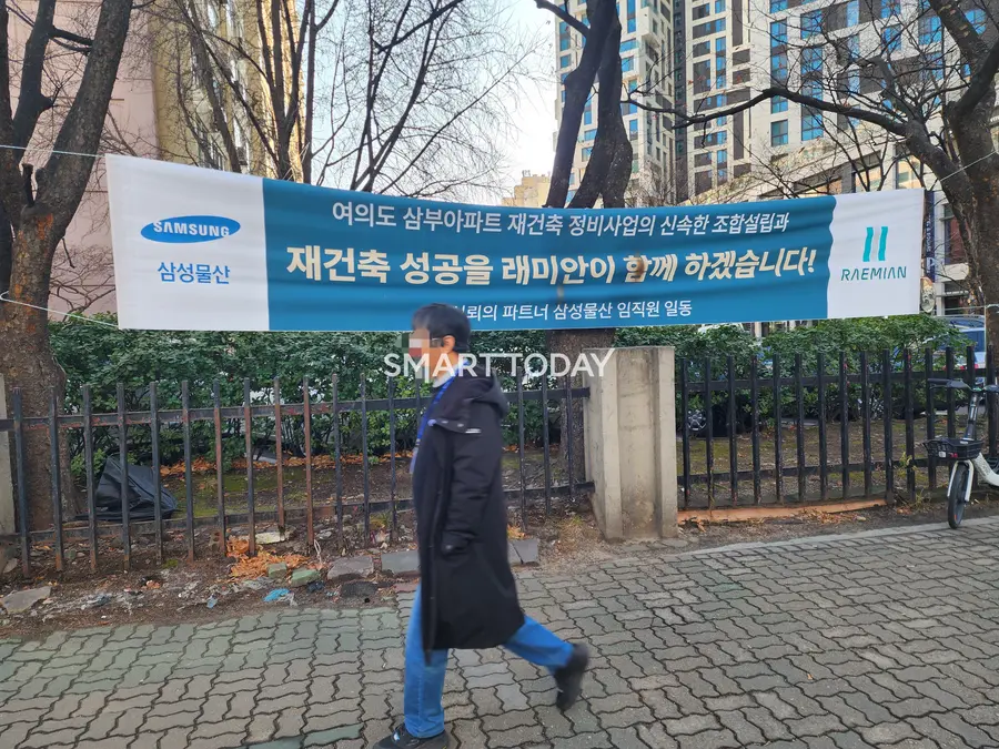 한 시민이 삼성물산의 여의도 삼부아파트 재건축 홍보 현수막 앞을 지나고 있다. 출처=김종현 기자