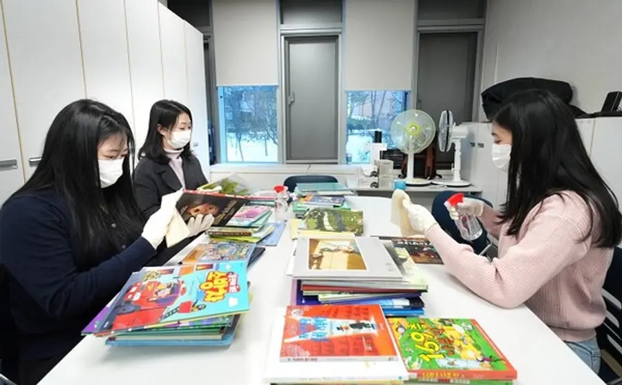 한국P&G 팸퍼스 임직원들이 리모델링된 대기 공간에서 소아 환자를 위한 동화책을 소독하고 있다.