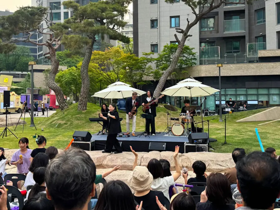 디에이치 자이 개포 단지 내 중앙광장에서 열린 ‘잔디밭 뮤직 페스티벌’에서 입주민들이 가수 난아진과 쿨재즈밴드의 공연을 즐기고 있다. (사진제공=현대건설)