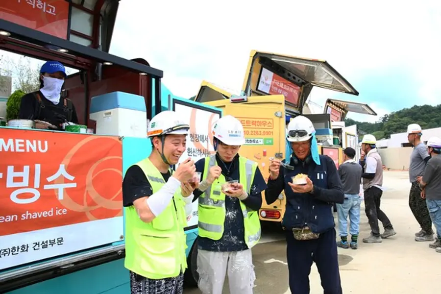 한화 건설부문이 건설현장 근로자들이 셈머 세이프트티 푸드트럭이 제공한 팥빙수를 먹고 있다. (사진제공=한화 건설)