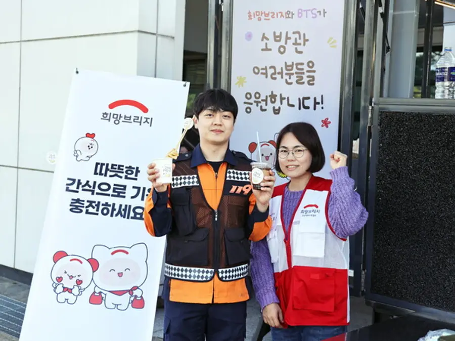 희망브리지 직원과 괴산소방서 소방대원이 간식차 앞에서 함께 기념사진을 찍고 있다. 이번 지원은 방탄소년단 이름으로 기부된 기부금으로 진행됐다.(사진제공=희망브리지)