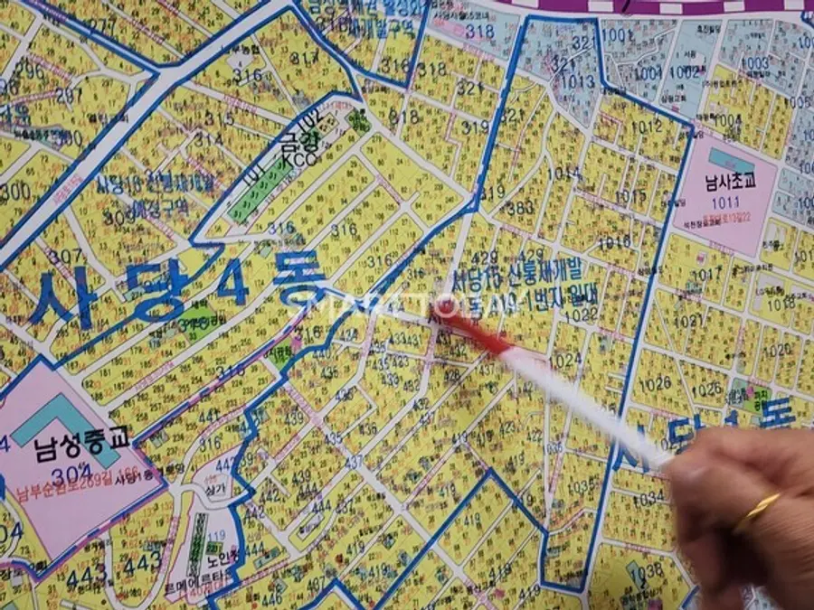 공인중개사 관계자가 지도에서 사당15구역 재개발 지구를 가리키고 있다. 출처=김종현 기자