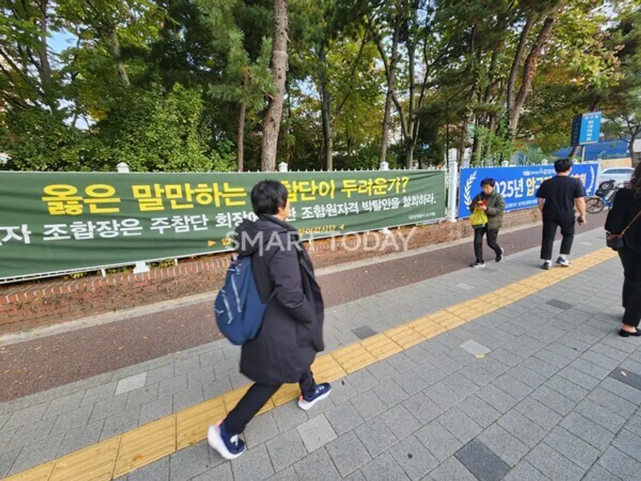 (왼쪽부터) 압구정3구역 조합을 비판하는 주참위의 현수막과 조합 총회를 안내하는 현수막이 인도 옆 벽에 걸려있다. 출처=김종현 기자