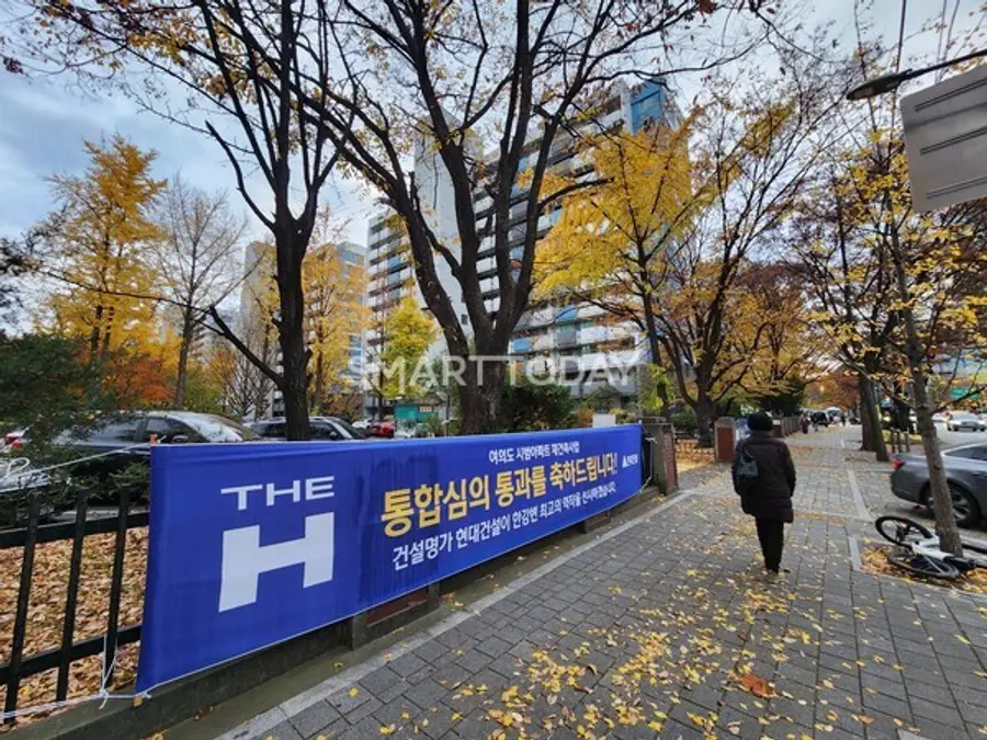 현대건설의 '여의도 시범아파트 재건축 통합심의 축하' 플랜카드가 걸린 시범아파트 입구 부근을 한 시민이 지나가고 있다. 출처=김종현 기자