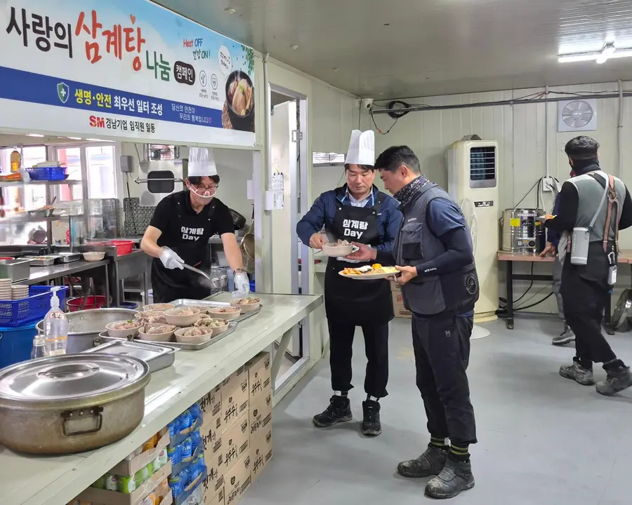 (왼쪽부터) 이기동 경남기업 대표이사와 성유진 건축사업실장이 경기 양주 옥정 A-22블록(BL) 아파트 건설 1공구 현장에서 혹서기 온열질환 예방 캠페인의 일환으로 진행된 ‘삼계탕 Day’에 배식자로 나서 근로자들에 삼계탕을 나눠주고 있다. 출처=SM그룹
