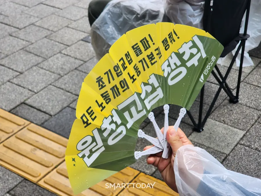 집회에 참가한 노조 관계자가 원청교섭 쟁취 문구가 적힌 플라스틱 우산을 펼치고 있다. 출처=김종현 기자