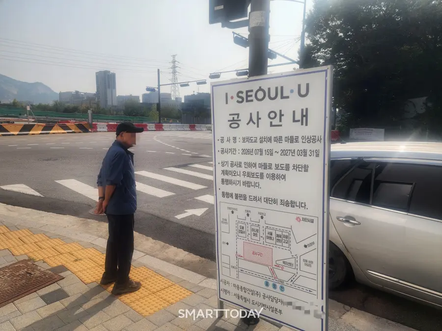 한 시민이 서울아레나 일대 공사안내판 앞에서 보행신호를 기다리고 있다. 출처=김종현 기자