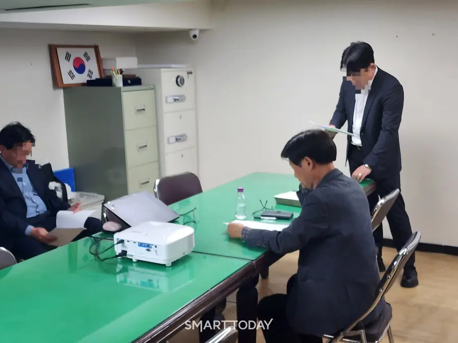 (오른쪽에서 두 번째) 전영진 대치우성1차·쌍용2차 재건축 조합장이 현장설명회 진행 전 관련 서류를 읽고 있다. 출처=김종현 기자